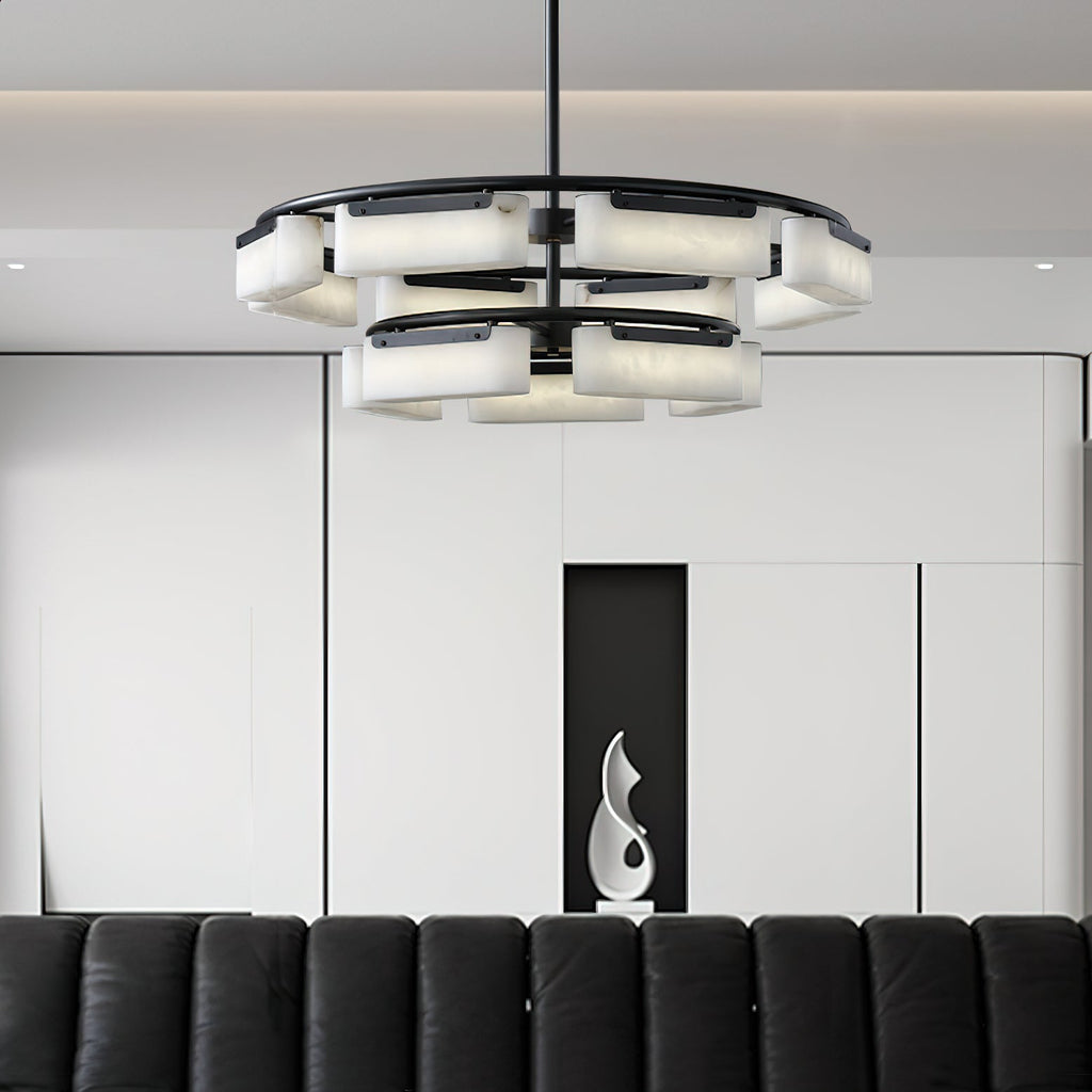 Clérachic Two-Tier Alabaster Ring Chandelier lit low over a black leather sofa in a pale panelled living room.