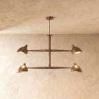 Clérachic chandelier in vintage brass, four cone shades on a crossbar frame beneath a plaster ceiling.