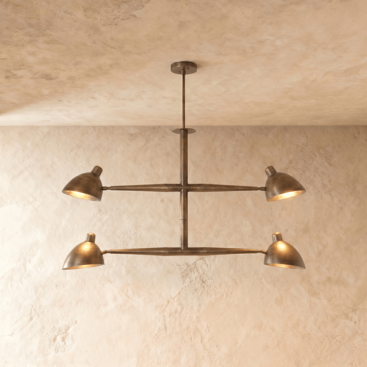 Clérachic chandelier in vintage brass, four cone shades on a crossbar frame beneath a plaster ceiling.