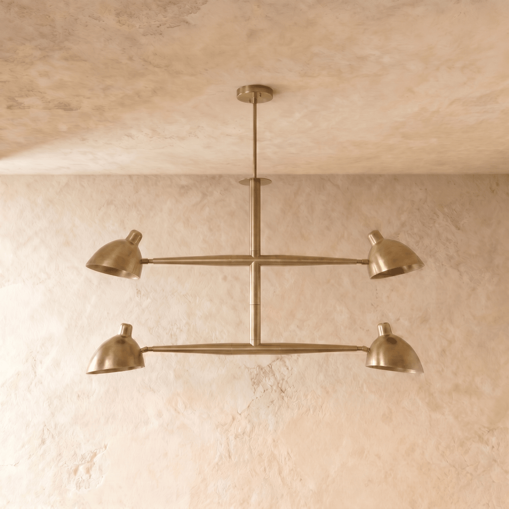 Clérachic chandelier in brushed brass shown from another angle, its crossbar arms catching warm light.