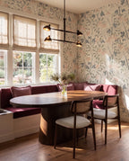 Clérachic chandelier in matte black above a burgundy banquette in a floral-wallpapered dining nook.