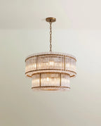 Clérachic mid-size two-tier chandelier in antiqued brass, its fluted glass rods and slim brass uprights glowing on a chain.