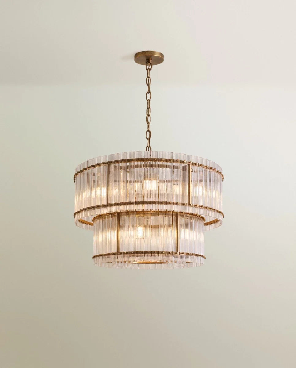 Clérachic mid-size two-tier chandelier in antiqued brass, its fluted glass rods and slim brass uprights glowing on a chain.