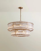 Clérachic wide two-tier chandelier in antiqued brass with a broad upper ring and fluted clear glass rods, hung on a brass chain.