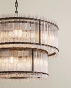 Clérachic close view of the matte black chandelier, showing dark riveted bands holding fluted glass rods in two tiers.
