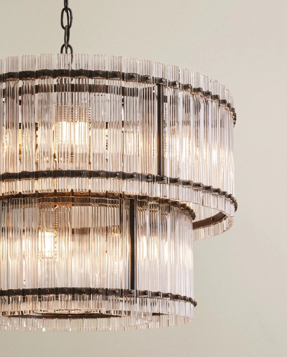 Clérachic close view of the matte black chandelier, showing dark riveted bands holding fluted glass rods in two tiers.