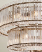 Clérachic close view of the polished nickel chandelier, showing riveted metal bands holding two tiers of fluted glass rods.