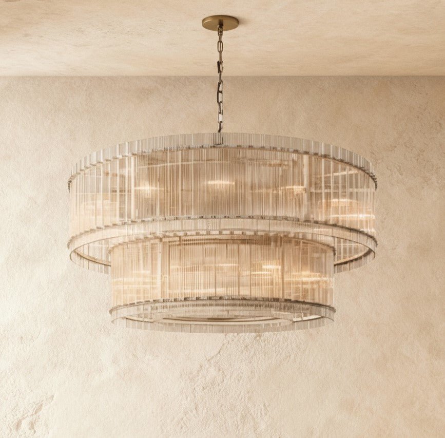 Clérachic wide two-tier chandelier with fluted clear glass rods and metal bands, hung on a chain against textured plaster.