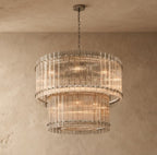 Clérachic two-tier chandelier with fluted clear glass rods and a pewter-toned canopy and chain, on a darker plaster wall.