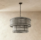 Clérachic matte black two-tier chandelier with a black chain and canopy, hung over a plaster wall in soft daylight.