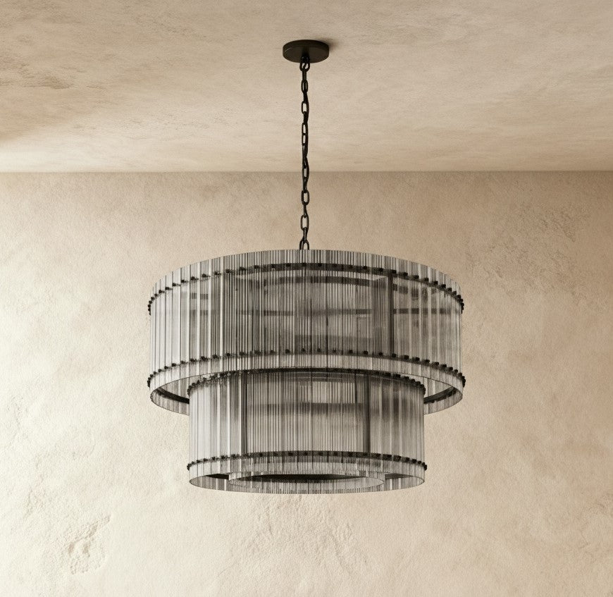 Clérachic matte black two-tier chandelier with a black chain and canopy, hung over a plaster wall in soft daylight.