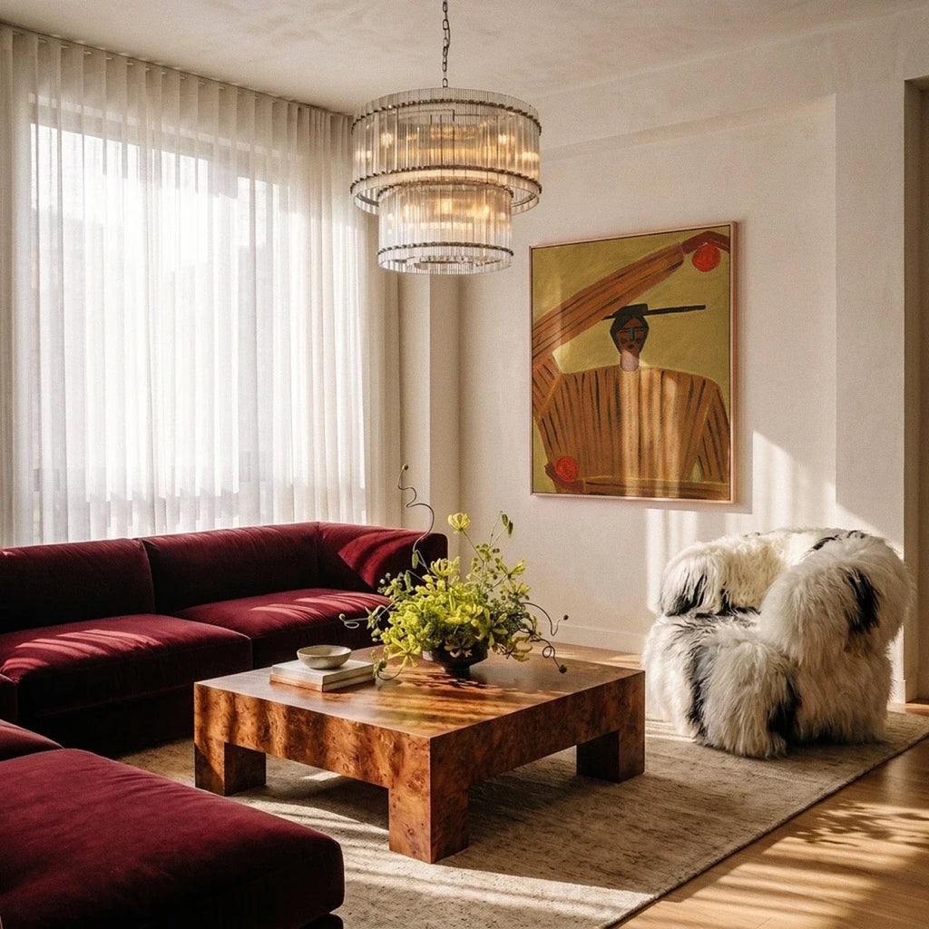 Clérachic two-tier fluted glass chandelier above a burr-wood coffee table and a burgundy velvet sofa in a bright living room.
