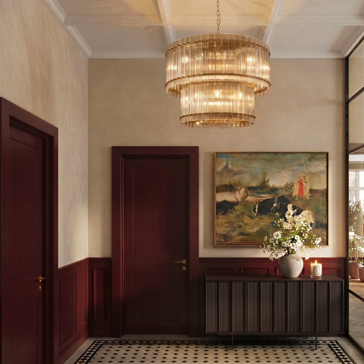 Clérachic antiqued brass two-tier chandelier hung in a panelled entrance hall with a patterned tile floor and a landscape painting.