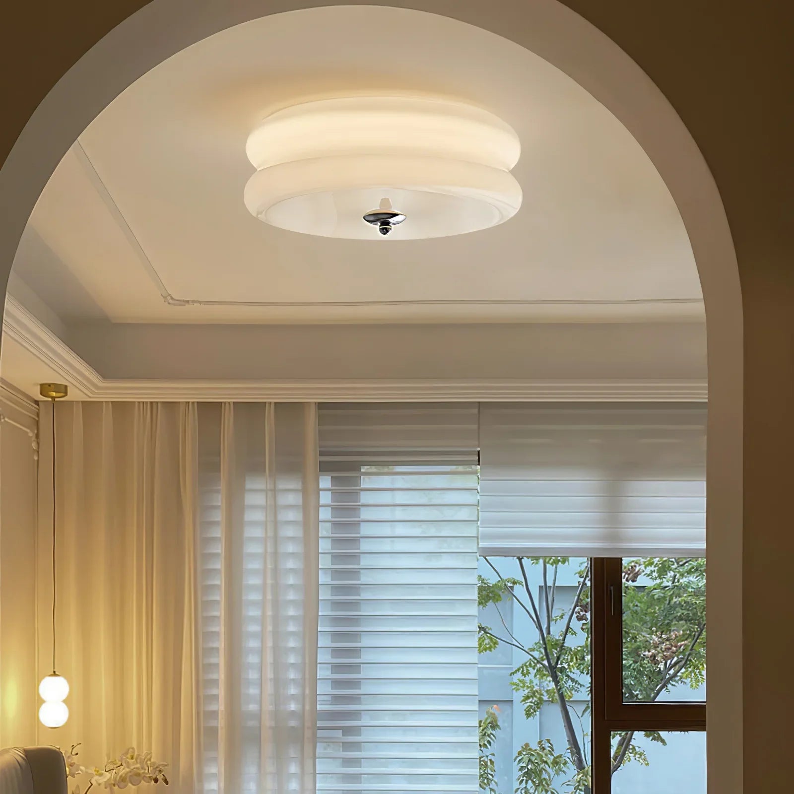 Clérachic two-tier flush mount ceiling light glowing warm above an arched living room doorway, chrome finial below.