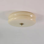 Clérachic two-tier flush mount ceiling light in beige glass, unlit, showing the gold finial at the centre underside.
