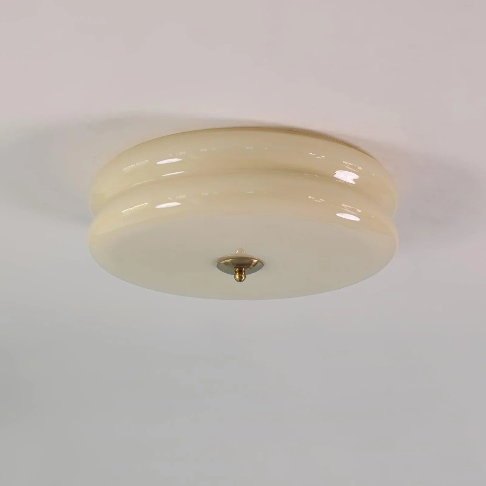 Clérachic two-tier flush mount ceiling light in beige glass, unlit, showing the gold finial at the centre underside.