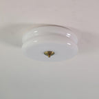 White glass Clérachic two-tier flush mount ceiling light with a gold finial, sitting flat against a plain ceiling.