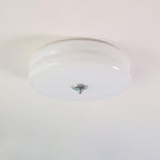 White opal Clérachic two-tier flush mount ceiling light seen from below, chrome finial centred on the flat underside.