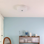Clérachic two-tier flush mount ceiling light in white glass lighting a blue bedroom with a mirror and reeded cabinet.