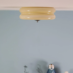 Close crop of the beige Clérachic two-tier flush mount ceiling light at the ceiling edge above a soft blue wall.