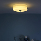 Clérachic two-tier flush mount ceiling light lit at night, warm glow spilling across the ceiling above a dark wall.