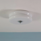 White Clérachic two-tier flush mount ceiling light unlit on a white ceiling, a blue wall running below it.