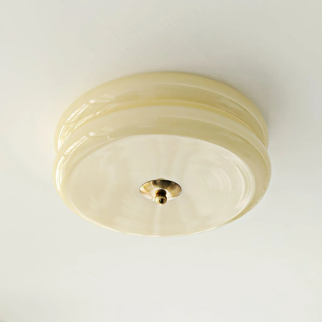 Clérachic two-tier flush mount ceiling light viewed straight from below, brass finial centred on the cream glass.