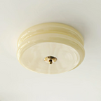 Clérachic two-tier flush mount ceiling light viewed straight from below, brass finial centred on the cream glass.