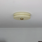 Small beige Clérachic two-tier flush mount ceiling light on a white ceiling beside a moulded plaster cornice.