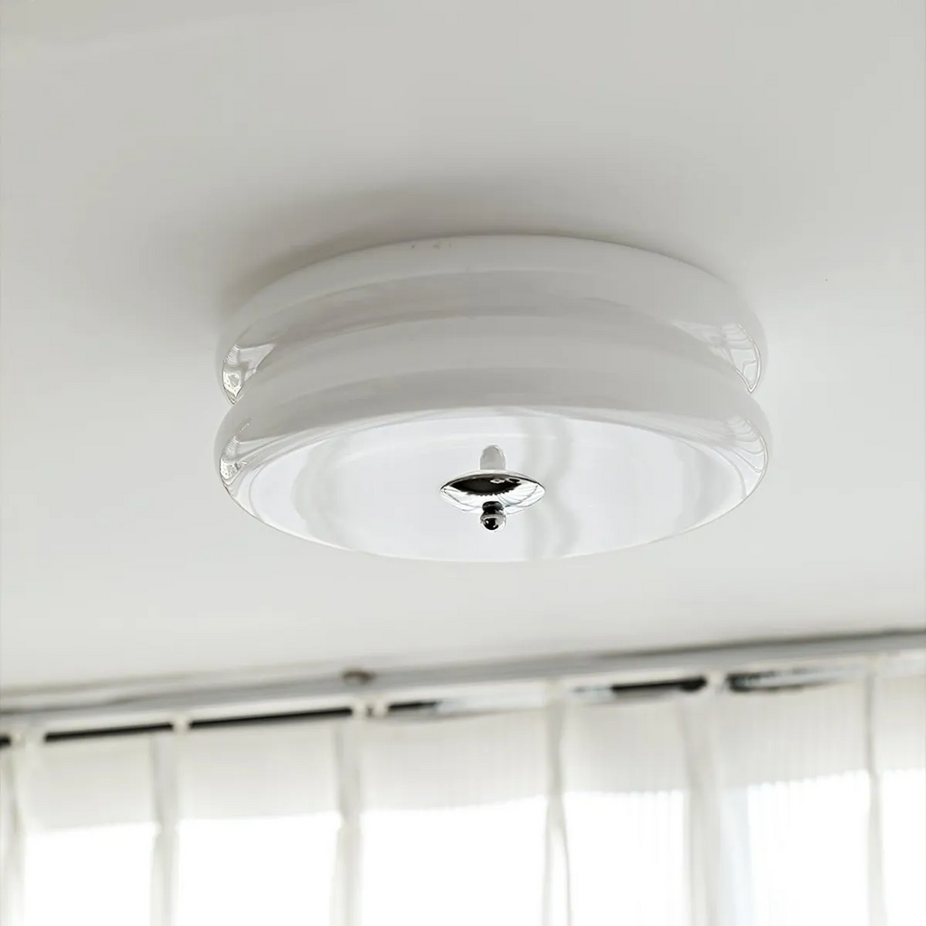 White glass Clérachic two-tier flush mount ceiling light with a chrome finial above sheer curtains at a window.