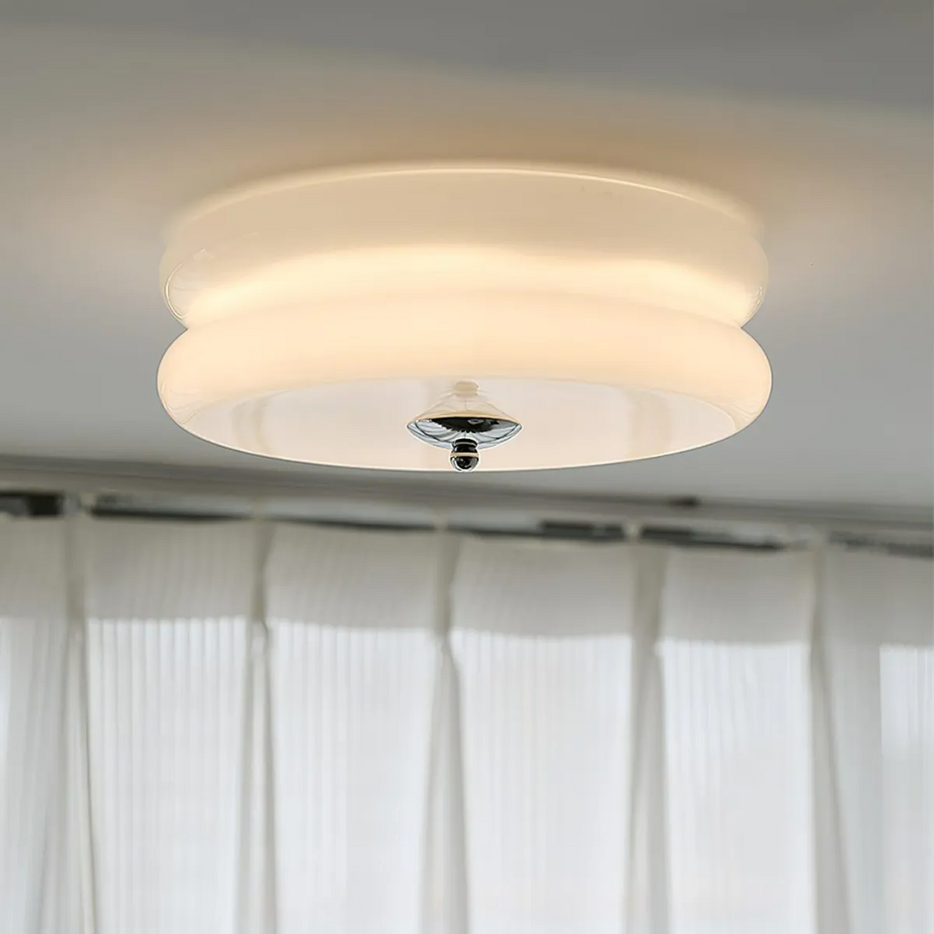 Lit Clérachic two-tier flush mount ceiling light in white glass, chrome finial glowing above sheer curtains.