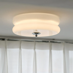 Lit Clérachic two-tier flush mount ceiling light in white glass, chrome finial glowing above sheer curtains.