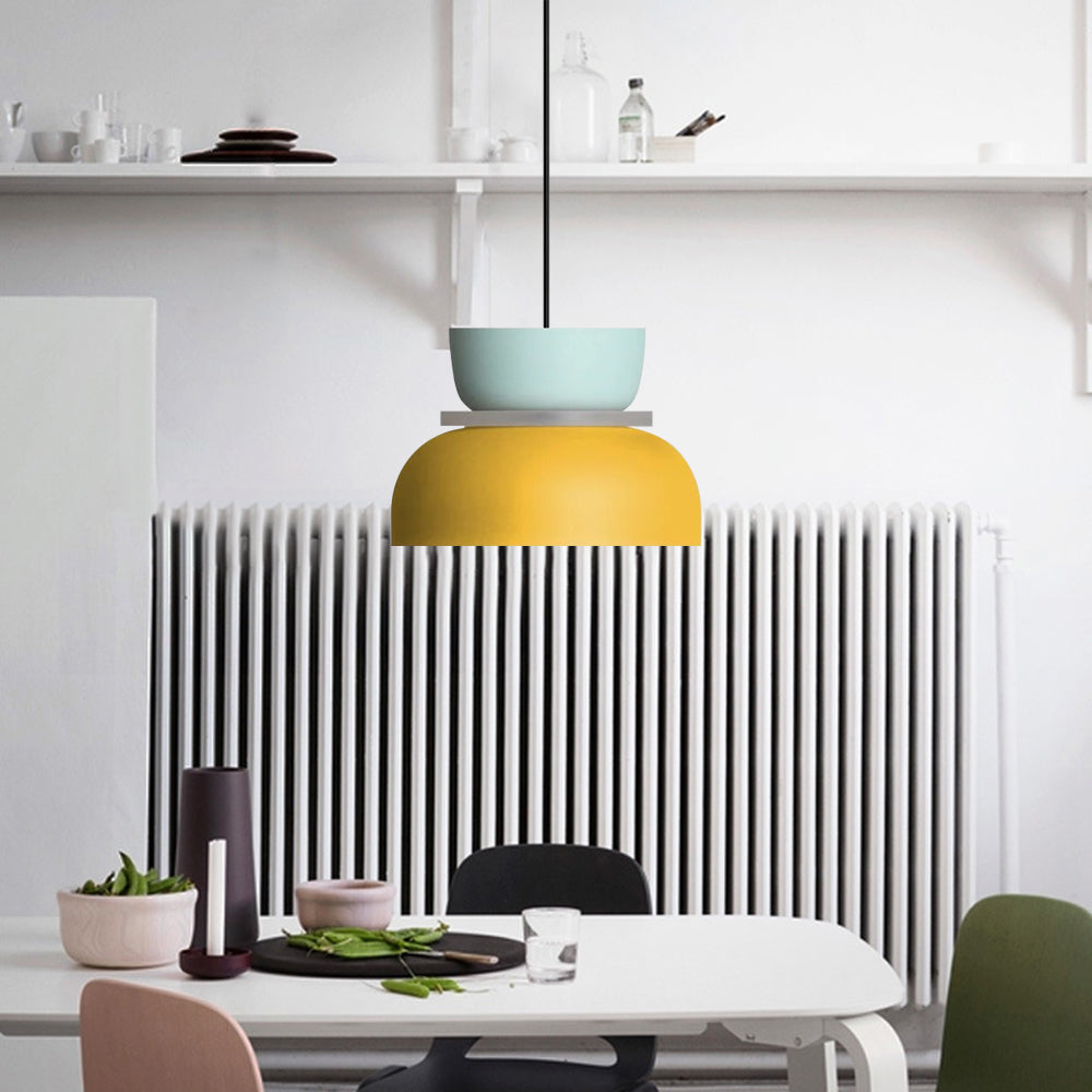 A Clérachic two-tone dome pendant in mint blue and yellow hangs over a dining table beside a kitchen radiator.