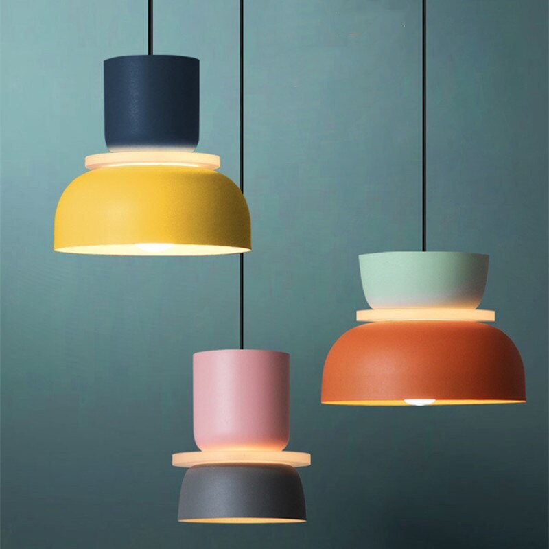 Three Clérachic two-tone dome pendants in navy-yellow, pink-charcoal and mint-orange hang against a teal wall.