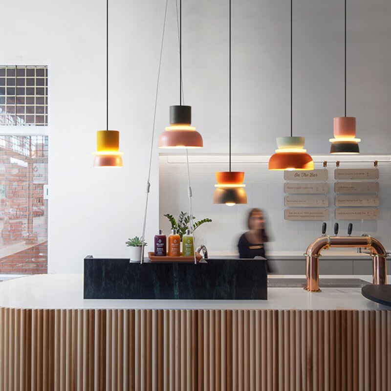 Five Clérachic two-tone dome pendants in mixed colourways hang above a café bar counter with a barista at work.