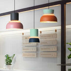 Three Clérachic two-tone dome pendants — charcoal-mauve, mint-navy and mint-orange — hang above a café menu board.