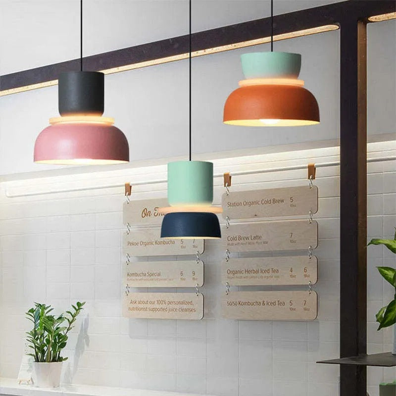 Three Clérachic two-tone dome pendants — charcoal-mauve, mint-navy and mint-orange — hang above a café menu board.