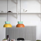 Two Clérachic two-tone dome pendants in mint-yellow and mint-orange hang side by side above a kitchen radiator.