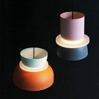 A Clérachic two-tone dome pendant tilted to show its lit diffuser ring and bulb holder inside the mint-orange shade.