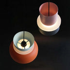 Two tilted Clérachic two-tone dome pendants reveal the glowing diffuser ring and bulb inside the mint-orange shade.