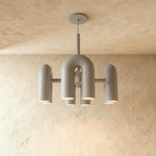 Clérachic chandelier of rounded U-shaped modules in soft grey, hanging from a slim stem against a warm limewashed plaster wall.