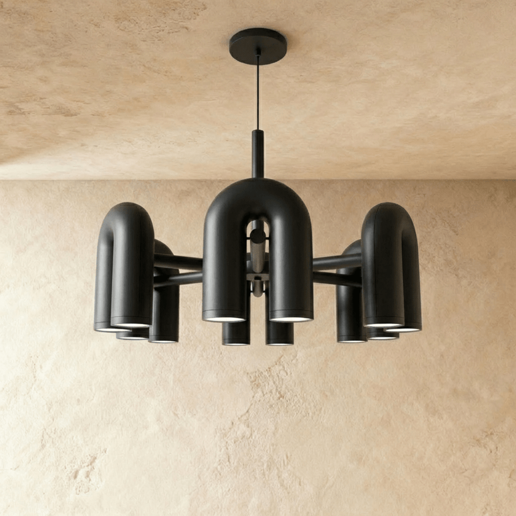 Clérachic larger chandelier with a fuller ring of black U-shaped arch modules, hung on a cable against a plaster wall.