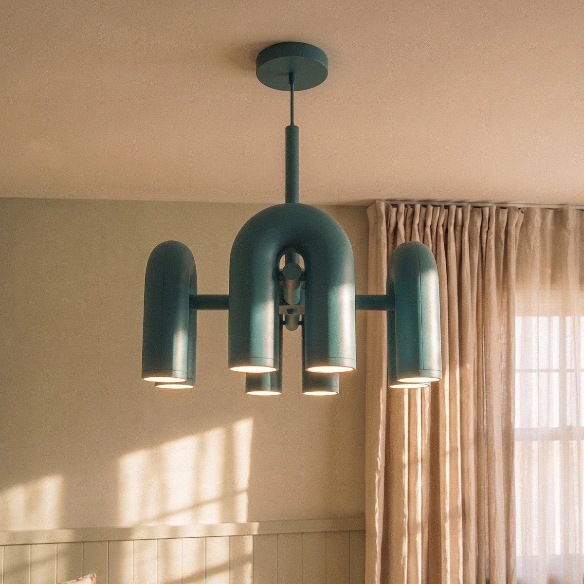 Clérachic blue arch-module chandelier close up beside linen curtains, its soft light glowing from the downlight openings.