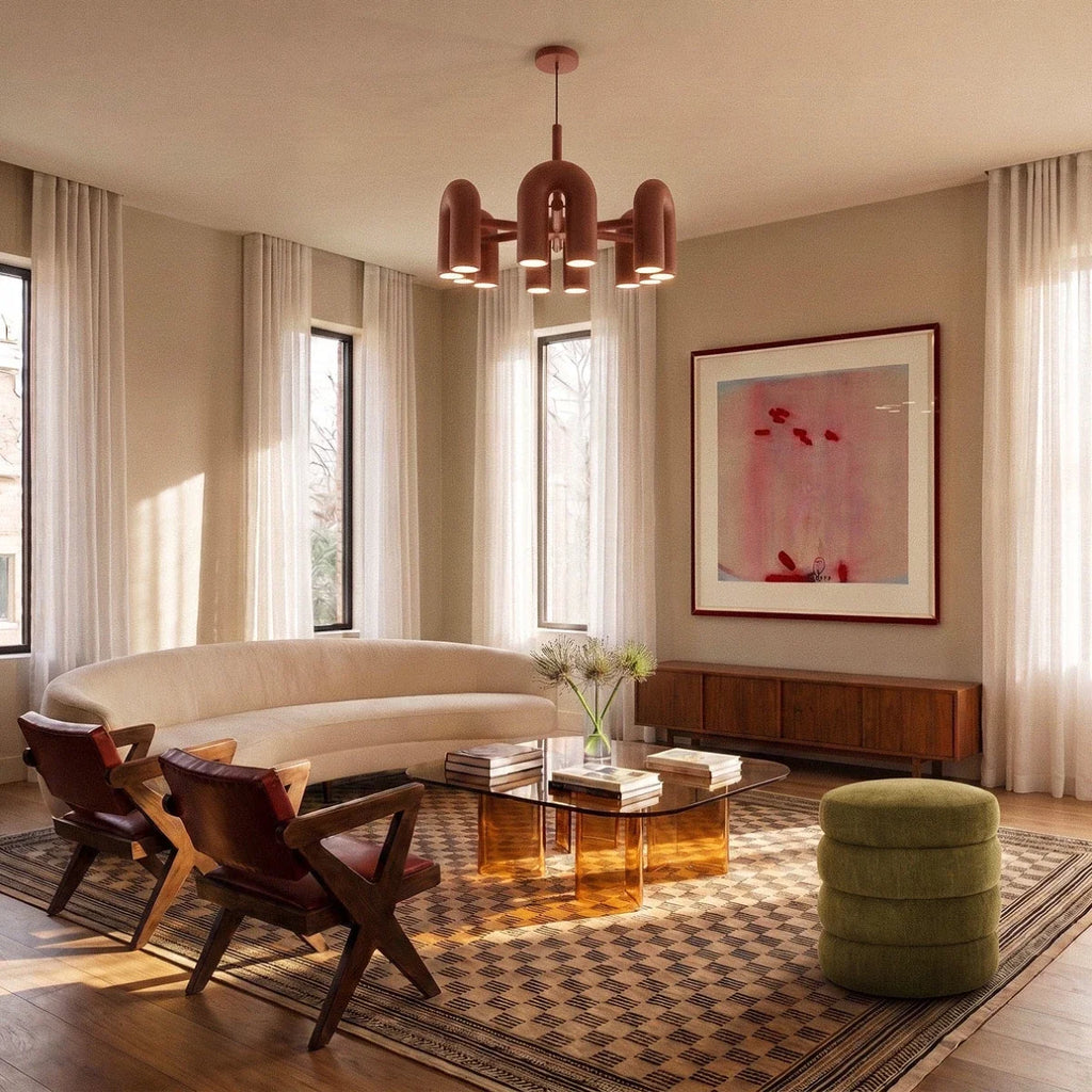Clérachic terracotta orange arch-module chandelier above a curved cream sofa and glass coffee table in a tall bright living room.