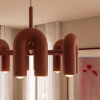 Clérachic terracotta orange chandelier close up, showing the smooth rounded arch modules, the central hub and warm glowing bulbs.