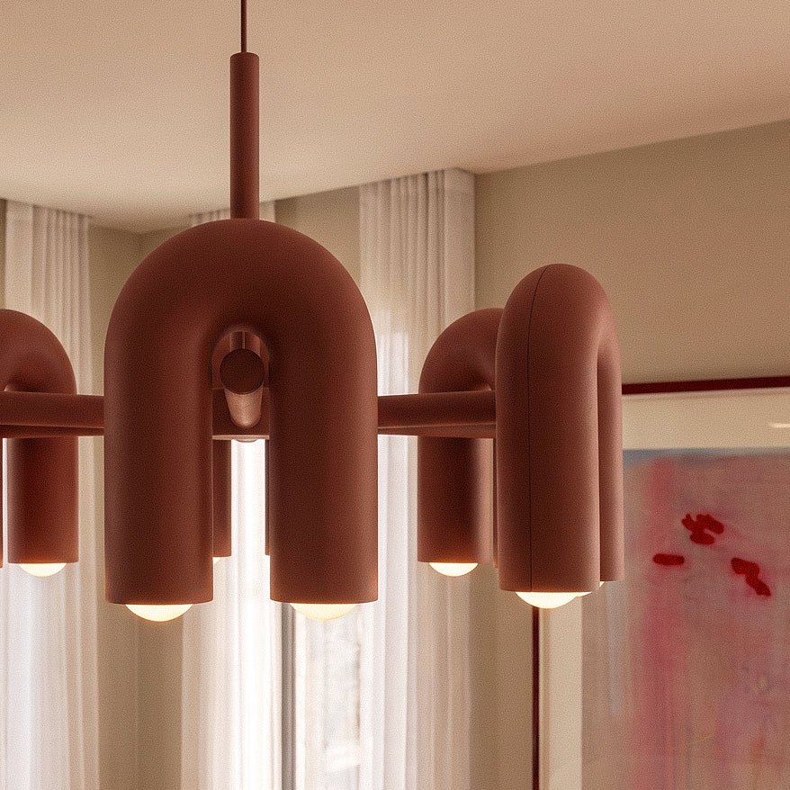Clérachic terracotta orange chandelier close up, showing the smooth rounded arch modules, the central hub and warm glowing bulbs.