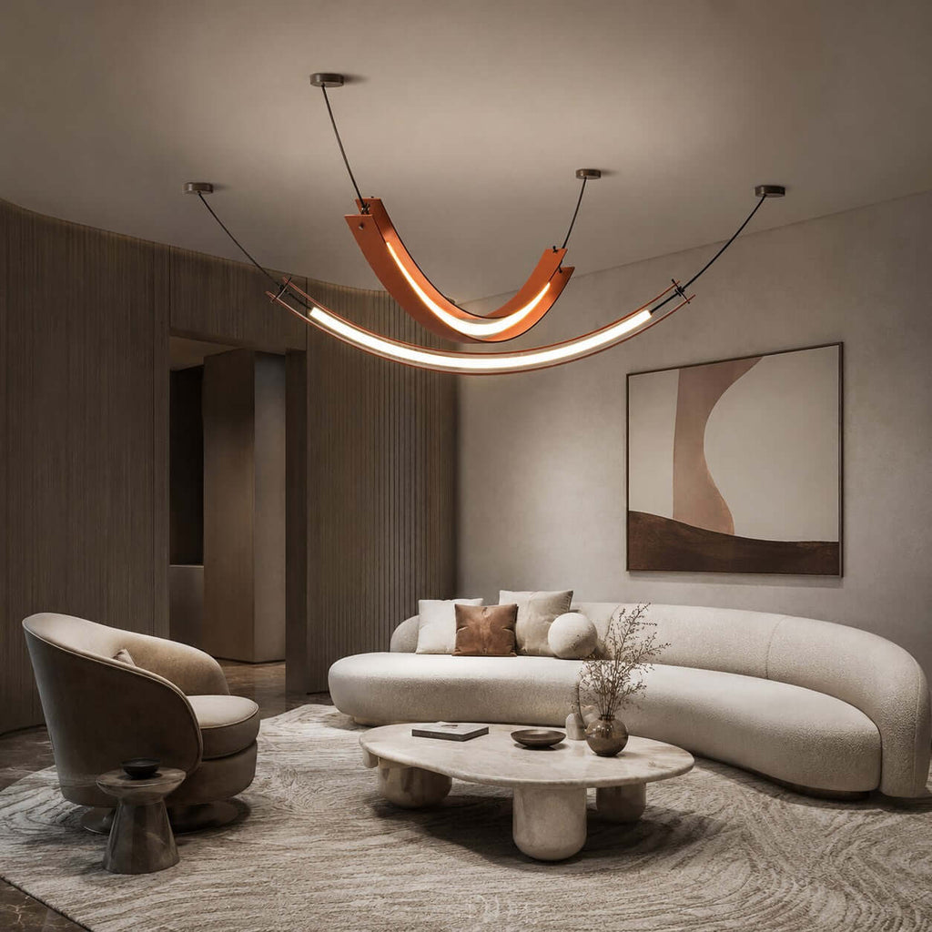 This Clérachic pendant, with a curved terracotta piece and a long lit strip below, hangs over a curved cream sofa and a low table.