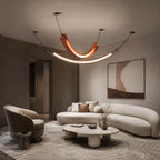 This Clérachic pendant, with a curved terracotta piece and a long lit strip below, hangs over a curved cream sofa and a low table.