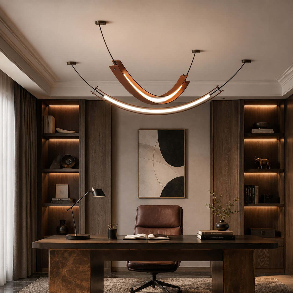 A Clérachic curved pendant with a long lit strip beneath hangs above a dark wood desk, framed by lit built-in shelves.