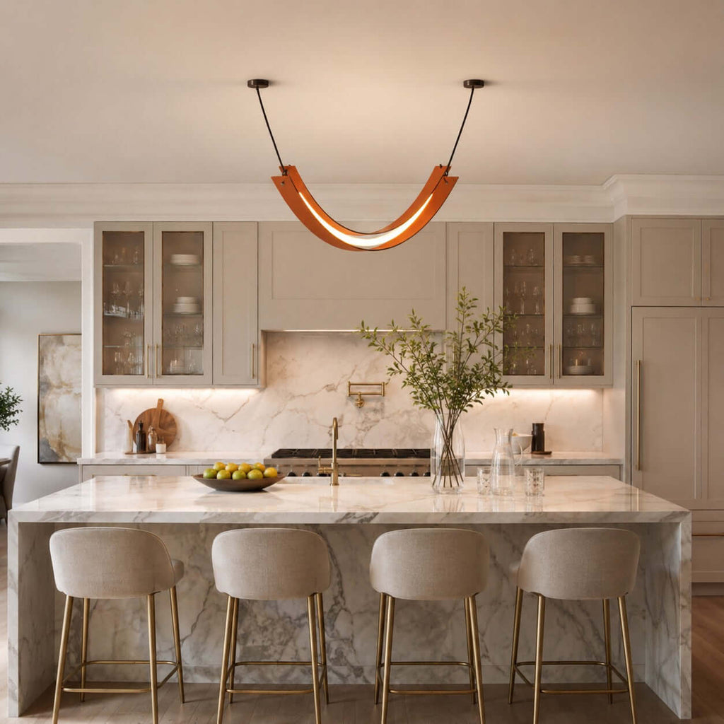 Terracotta-coloured Clérachic pendant over a marble kitchen island with four cream stools and glass-fronted cabinets behind.
